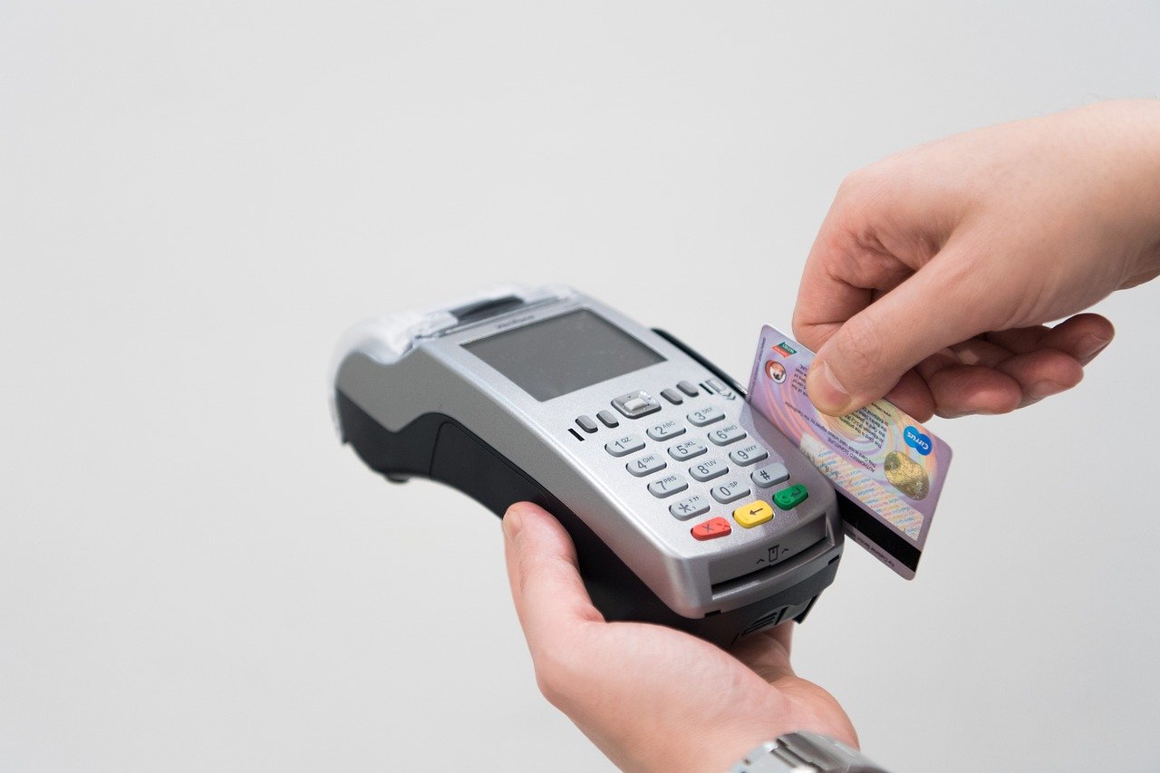 Man holding a POS terminal while swiping a credit card for ITD INNOVATION DUBAI.